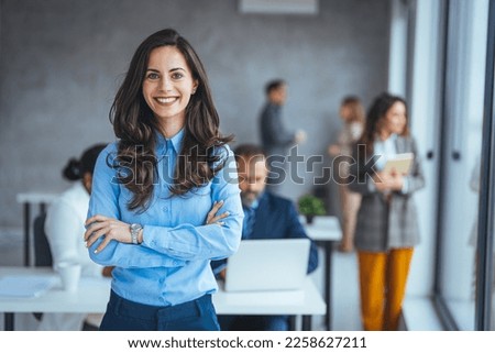 Shot of a confident young businesswoman standing in a modern office. Portrait of a businesswoman standing in the office. One Happy Pretty Business Woman Standing in office and looking at camera  Royalty-Free Stock Photo #2258627211