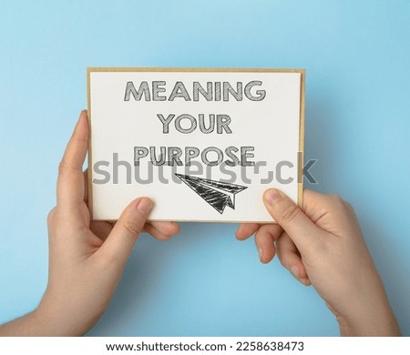 Person holds card with phrase Meaning Your Purpose on blue
