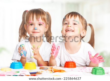 happy children twins girl draws paints , get dirty