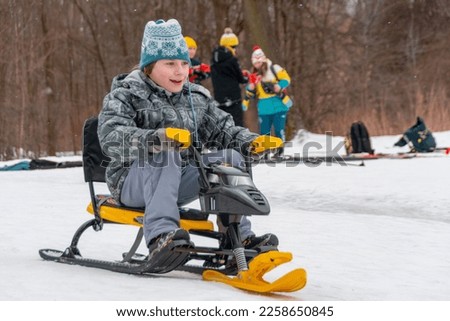 A boy rides a snowcat down a slide. Active winter holidays.