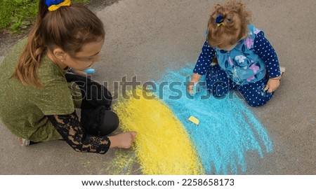 Children draw the Ukrainian flag on the pavement. Selective focus. Nature.