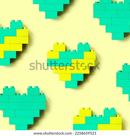 Hearts from blocks as background, minimal geometric pattern from plastic blocks mint and yellow color, shapes heart from child construction. Top view repeat pattern, Toys and games