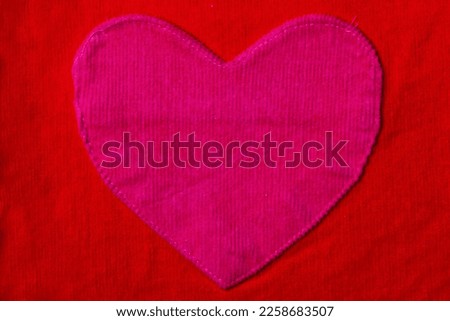 Closeup of large pink heart on red fabric background texture. Valentine's or motherâ€˜s day concept. Copy space.