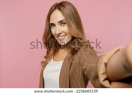 Close up young successful employee business woman 30s she wearing casual brown classic jacket doing selfie shot pov on mobile cell phone isolated on plain pastel light pink background studio portrait