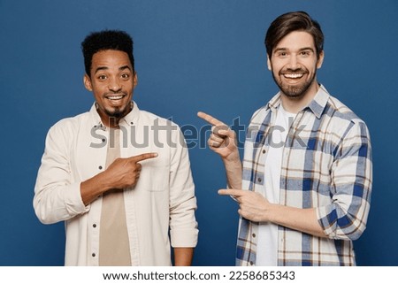 Young two friends cheerful smiling happy men wear white casual shirts looking camera together point index finger on each other isolated plain dark royal navy blue background. People lifestyle concept