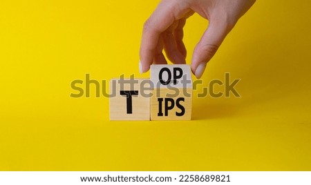 Top Tips symbol. Businessman hand Turnes cubes with words Top Tips. Beautiful yellow background. Business and Top Tips concept. Copy space