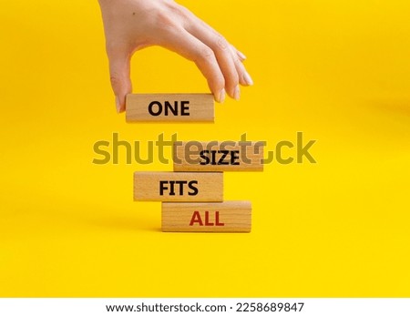 One size fits all symbol. Concept words One size fits all on wooden blocks. Beautiful yellow background. Businessman hand. Business and One size fits all concept. Copy space.