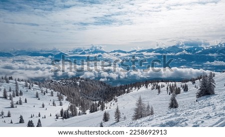 A snow capped slopes of Gerlitzen in Austria. There are endless snow capped mountain chains. Few tress in the middle of white slopes. Winter ski resort. Skiing remedy.