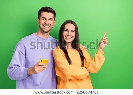 Photo of husband wife dressed sweatshirts showing empty space chatting twitter telegram facebook isolated green color background