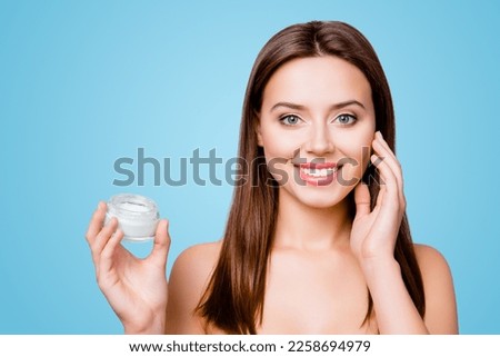 Concept of using moisturizing cream before going to bed. Beautiful cute pretty charming woman is holding a cream jar and applying it on her skin, isolated on grey background