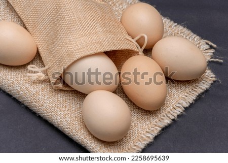 Fresh chicken eggs are scattered on a linen cloth on a dark background. Concept: eco-friendly eggs, household.