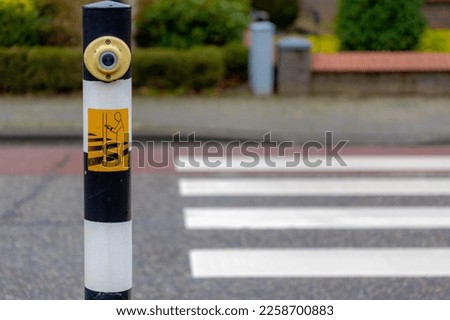 Selective focus of Pedestrian crossing button on the pole, Blurred crosswalk or zebra crossing in countryside road, Press the button and wait for the green light, Crossway on the street in Netherlands
