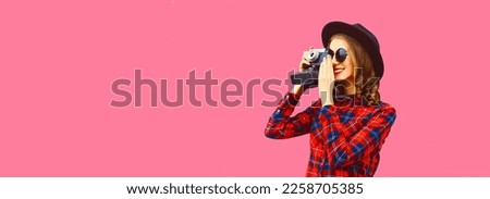 Portrait of happy smiling young woman photographer with film camera on pink background, blank copy space for advertising text
