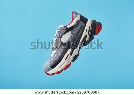 Stylish trendy sports shoes hanging on blue background. Men's fashion sport footwear. Air sneakers. Levitation concept. Flying colored leather sneakers isolated on a pastel background. Royalty-Free Stock Photo #2258708587