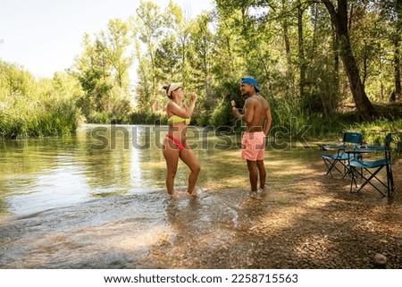 Interracial couple eating ice cream on the riverside