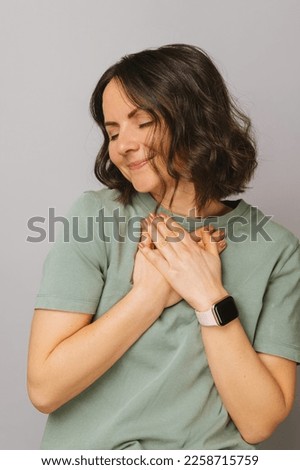 Close up vertical portrait of a woman with eyes closed holding hands over her chest because you are dear to her heart.