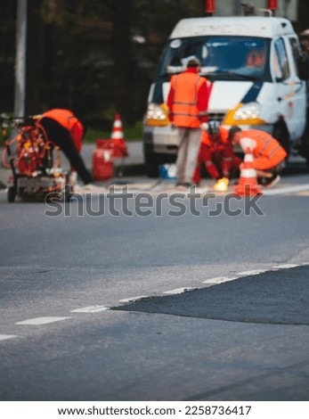 Process of making new road surface markings with a line striping machine, workers improve city infrastructure, demarcation marking of pedestrian crossing with a hot melted paint on asphalt pavement Royalty-Free Stock Photo #2258736417