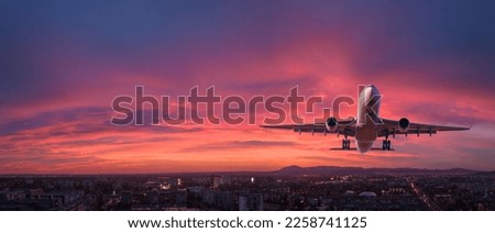 Airplane is flying in colorful sky over the city at night. Landscape with passenger airplane, skyline, purple sky with red and pink clouds. Aircraft is landing at sunset. Aerial view. Transport Royalty-Free Stock Photo #2258741125