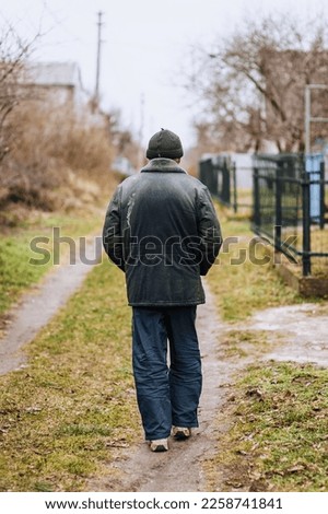 A lone man in dirty torn clothes, a beggar tramp, an old bum walks on the street in search of food. Photography, the concept of the problems of humanity, lifestyle. Royalty-Free Stock Photo #2258741841