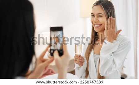 Wedding, ring and engagement with a woman or bride taking a photograph on a phone and drinking champagne with a friend. Happy, smile and celebration with an attractive young female and her bridesmaid