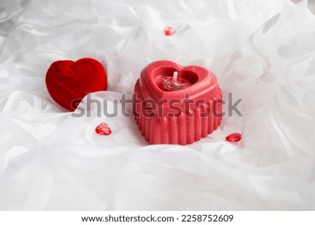 valentine's day background. candle in the shape of a heart made of natural soy wax in the shape of a heart and a bouquet of flowers