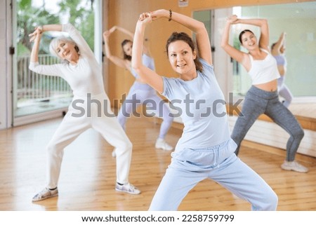 Active middle-aged woman practicing aerobic dance in training hall during fitness dance classes. Women training dance in hall Royalty-Free Stock Photo #2258759799