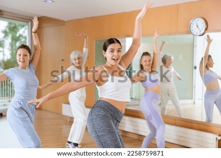 Dynamic young woman attendee of dance studio doing belly-dance during training session. Women training dance in hall Royalty-Free Stock Photo #2258759871