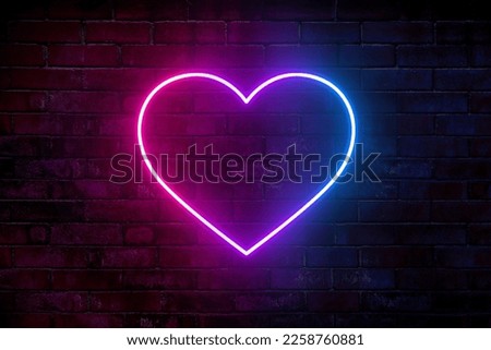 Neon heart with a glow on the background of a dark brick wall. Neon sign pink and blue.