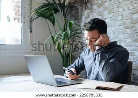 Unhappy young man looking at phone, feeling nervous of bad device work, internet disconnection, lost data or inappropriate online content. Anxious male user dissatisfied with application or service. Royalty-Free Stock Photo #2258783533