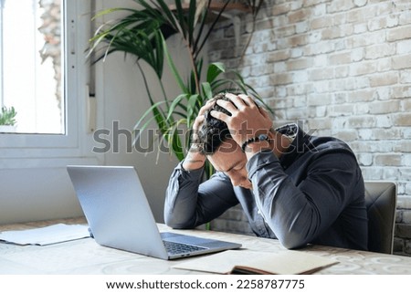 Unhappy young Caucasian male worker in glasses look at laptop screen shocked by gadget breakdown or operational problems. Frustrated man confused surprised by unexpected error on computer device. Royalty-Free Stock Photo #2258787775