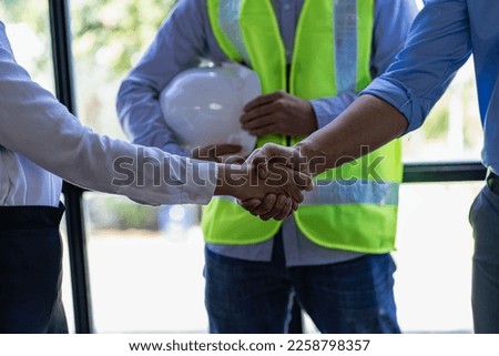 Successful collaboration concept, architect and construction engineer holding hands while working for teamwork and cooperation after completion of agreement in office Royalty-Free Stock Photo #2258798357
