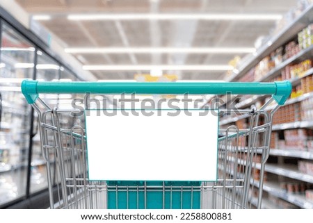 Blank banner attached to shopping cart, copy space with shopping cart on supermarket background for creative design, copy space to use in advertising communication Royalty-Free Stock Photo #2258800881