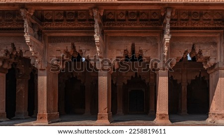 The architecture of the ancient Red Fort. Colonnade with openwork carved arches. Ornaments and patterns on walls and columns. India. Agra. Royalty-Free Stock Photo #2258819611