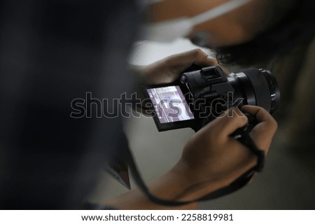 Close up of a man holding a modern photo camera while looking at the screen