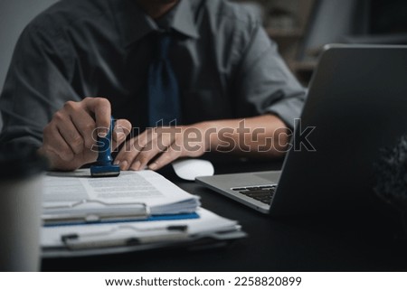 Man hand stamping approval signing on document or paperwork contract at desk.