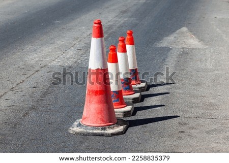 Traffic cones stand in a row on an asphalt road. Devices for temporary marking of roads. Avriynye cones stand on the road.