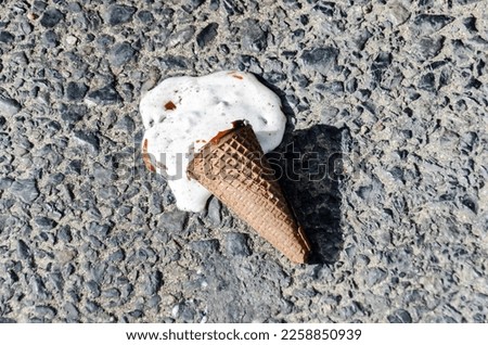 melted ice cream on the sidewalk on a hot summer day. ice cream in a chocolate cone fell to the ground and melted. selective focus.