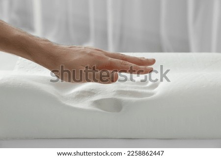 Man with orthopedic memory foam pillow indoors, closeup Royalty-Free Stock Photo #2258862447