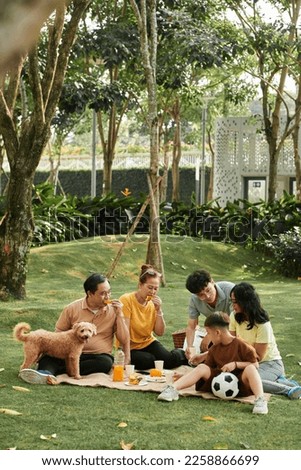 Big family with dog enjoying picnic in city park Royalty-Free Stock Photo #2258866699