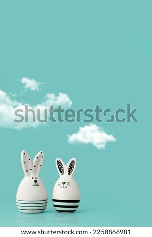 Statuettes of Easter rabbits 
under small clouds on the blue background. Festive picture with place for text