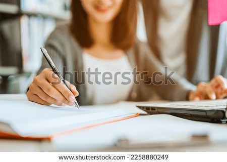 Asian woman students are reading and discussing about exam preparation. presentation, study for test preparation in library.Education, Learning, Student, Campus, University, Lifestyle concept. Royalty-Free Stock Photo #2258880249