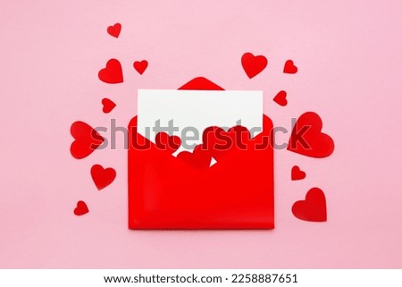 Red paper envelope with blank white note mockup inside and Valentines hearts on pink background. Flat lay, top view. Romantic love letter for Valentine's day concept
