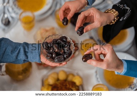 Happy Muslim family having iftar dinner to break fasting during Ramadan dining table at home group of Islamic people eating a healthy food dates together sharing and giving. Royalty-Free Stock Photo #2258889183