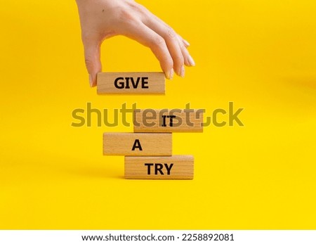 Give it a try symbol. Concept words Give it a try on wooden blocks. Beautiful yellow background. Businessman hand. Business and Give it a try concept. Copy space.