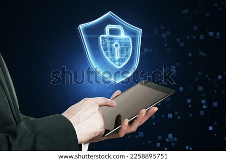 Close up of businessman pointing at tablet with glowing padlock hologram on dark blurry background. Secure, safety and web concept