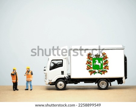 Mini toy at table with white background. Industrial shipping concept. Tomsk Oblast flag design,  is a federal subject of Russia (an oblast).