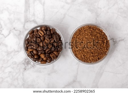 Coffee granules and coffee beans on a white marble background. Instant coffee drink. Energy hot drink. Place for text. Place for copy. Cheerful morning concept.