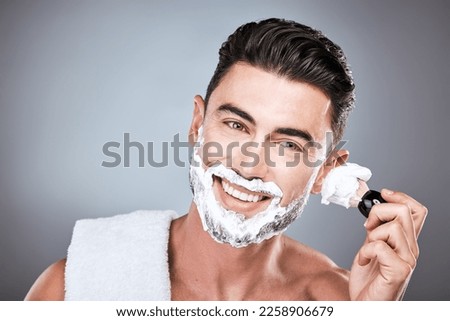 Brush, shaving cream and face of man in studio isolated on a gray background for hair removal. Beard care portrait, skincare and male model with facial product, foam or gel to shave for wellness. Royalty-Free Stock Photo #2258906679