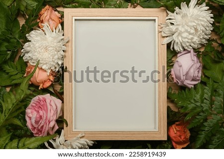 Blank picture frame surrounded by colorful spring flower and green leaves. Floral frame, spring or summer background Royalty-Free Stock Photo #2258919439
