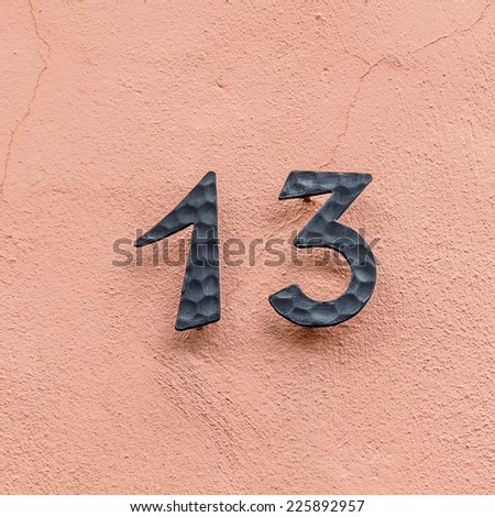 house number thirteen at a pink wall